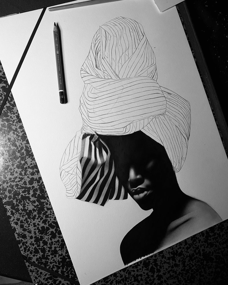 La Femme in progress: the face is finished while the headwrap is still a line drawing, a pencil lying beside the sheet.
